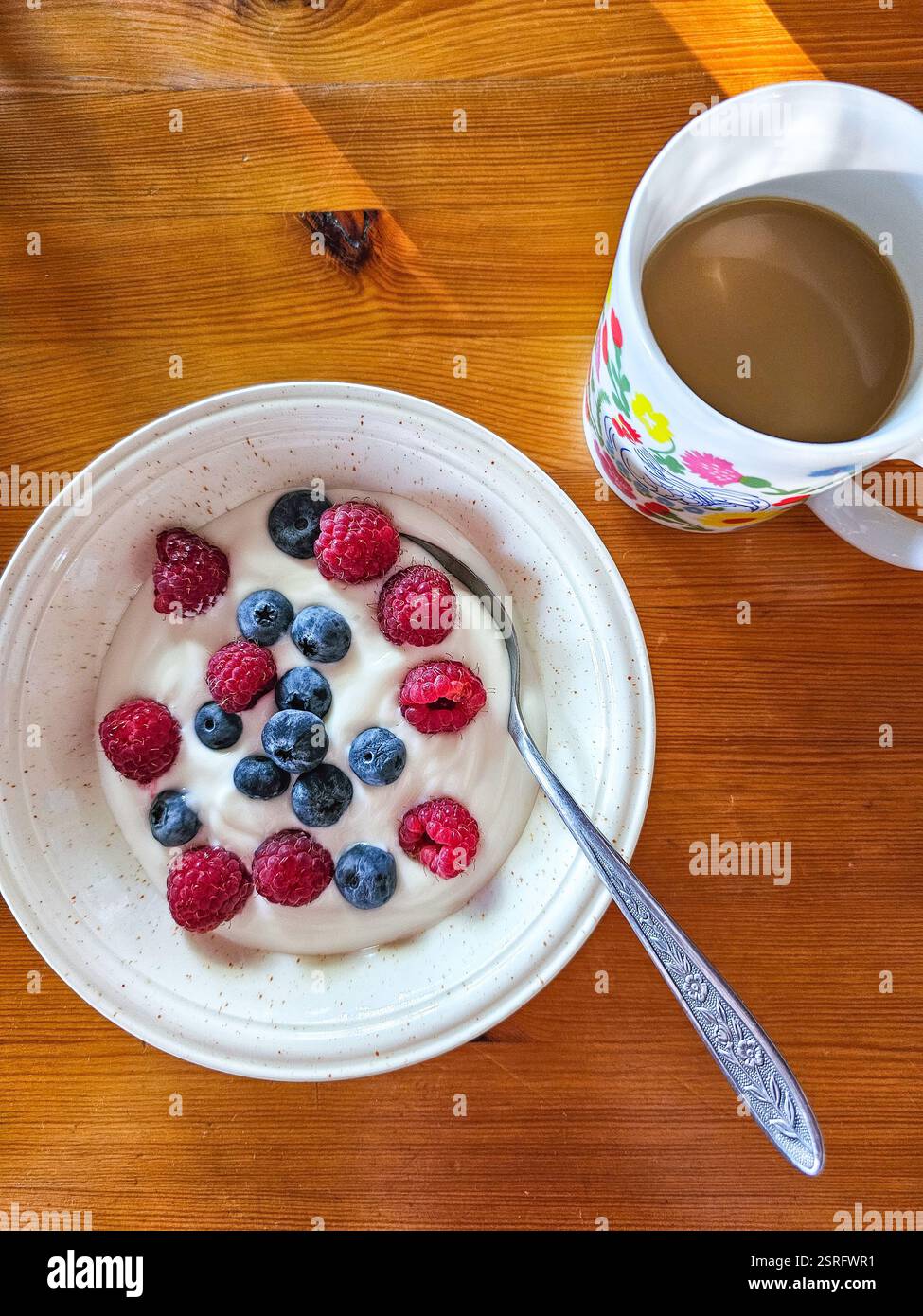 Gesundes Frühstück mit einer Tasse Kaffee und Joghurt mit Waldbeeren - Smartphone-aufgenommenes Stockfoto