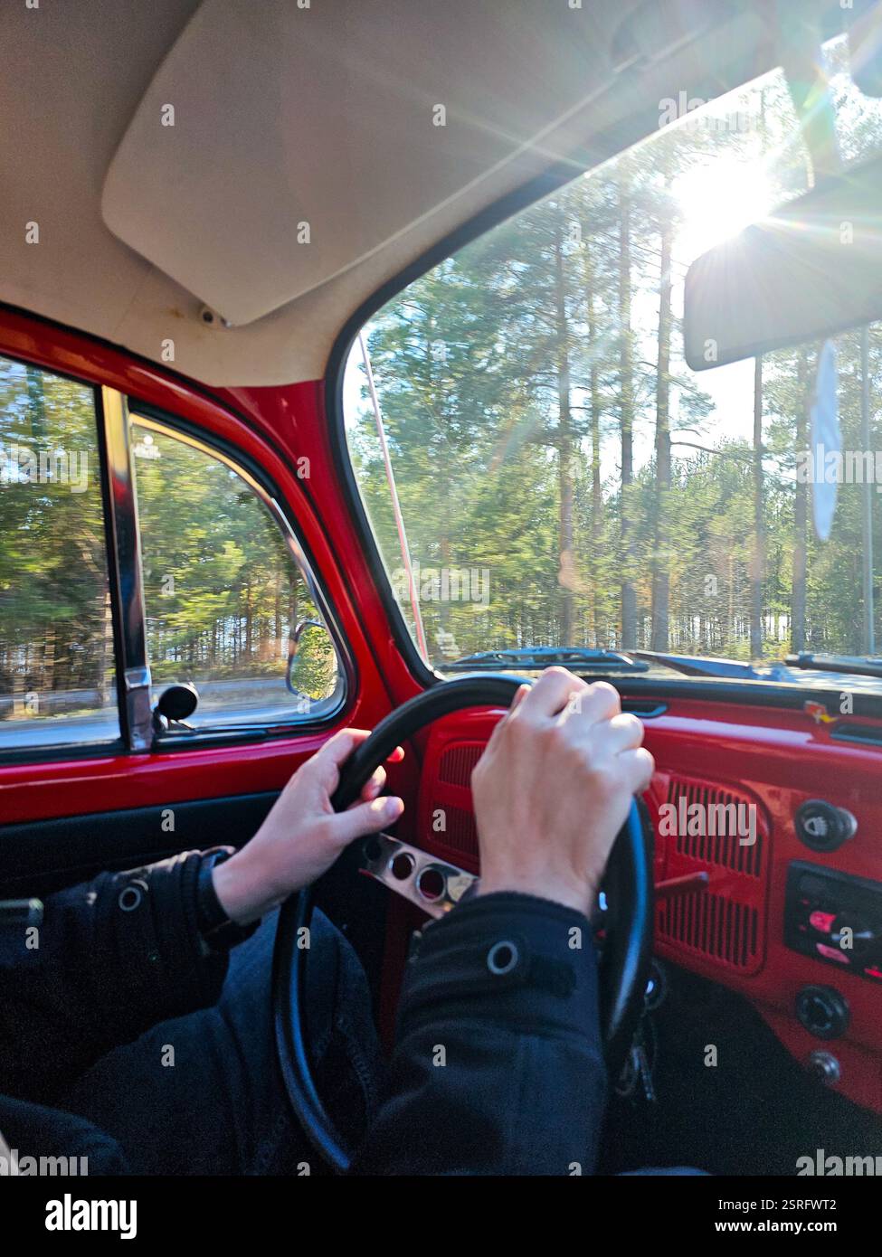 Person, die ein rotes Auto fährt - Smartphone-aufgenommenes Stockfoto