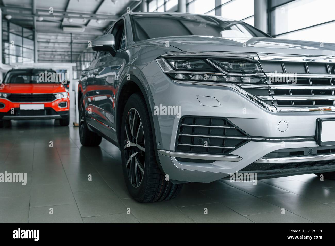 Vorderansicht des modernen neuen silberfarbenen Autos und eines roten hinter dem Auto. Stockfoto