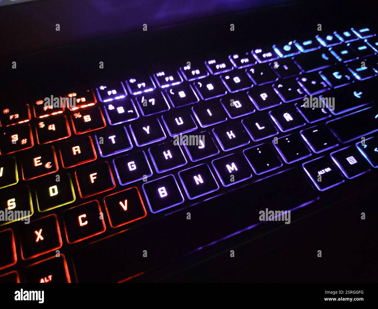 Hintergrundbeleuchtete Laptoptastatur mit RGB-Leuchten, die die Farbe in verschiedenen Abschnitten ändern. Die Beleuchtung variiert zwischen Rot-, Blau- und Violetttönen, was zu einem Ergebnis führt Stockfoto