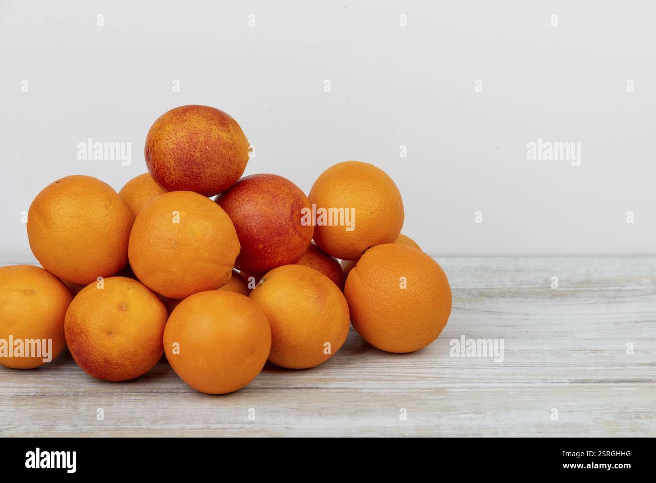 Gesunde Orangen gestapelt auf einem hellen Holztisch, Vitamin C Stockfoto