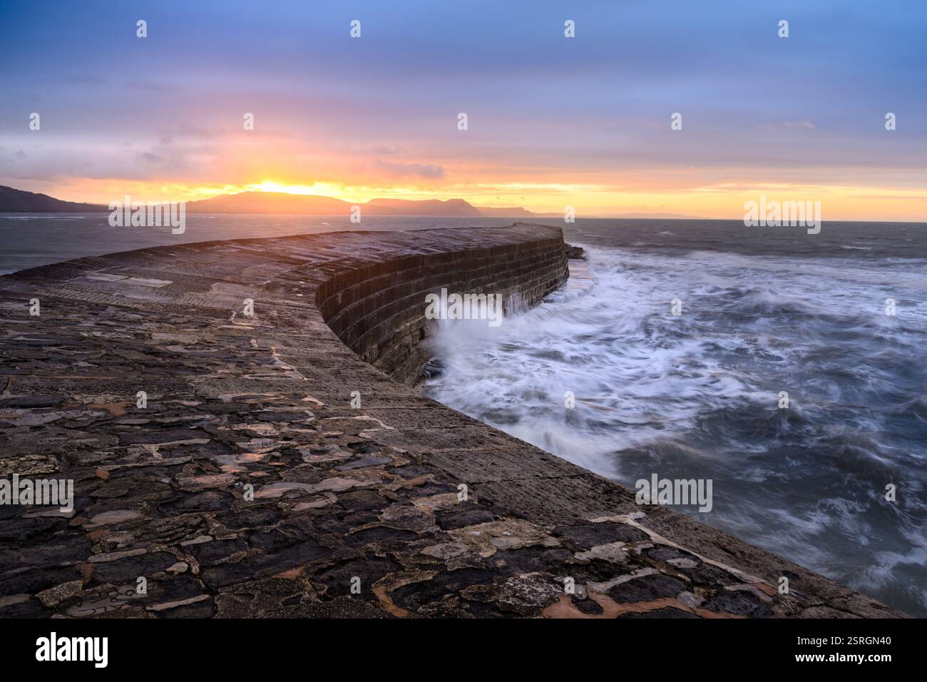 Sonnenaufgang im Cobb auf Lyme Regis mit dramatischen Wellen im Ozean. Dorset, England, Großbritannien. Stockfoto