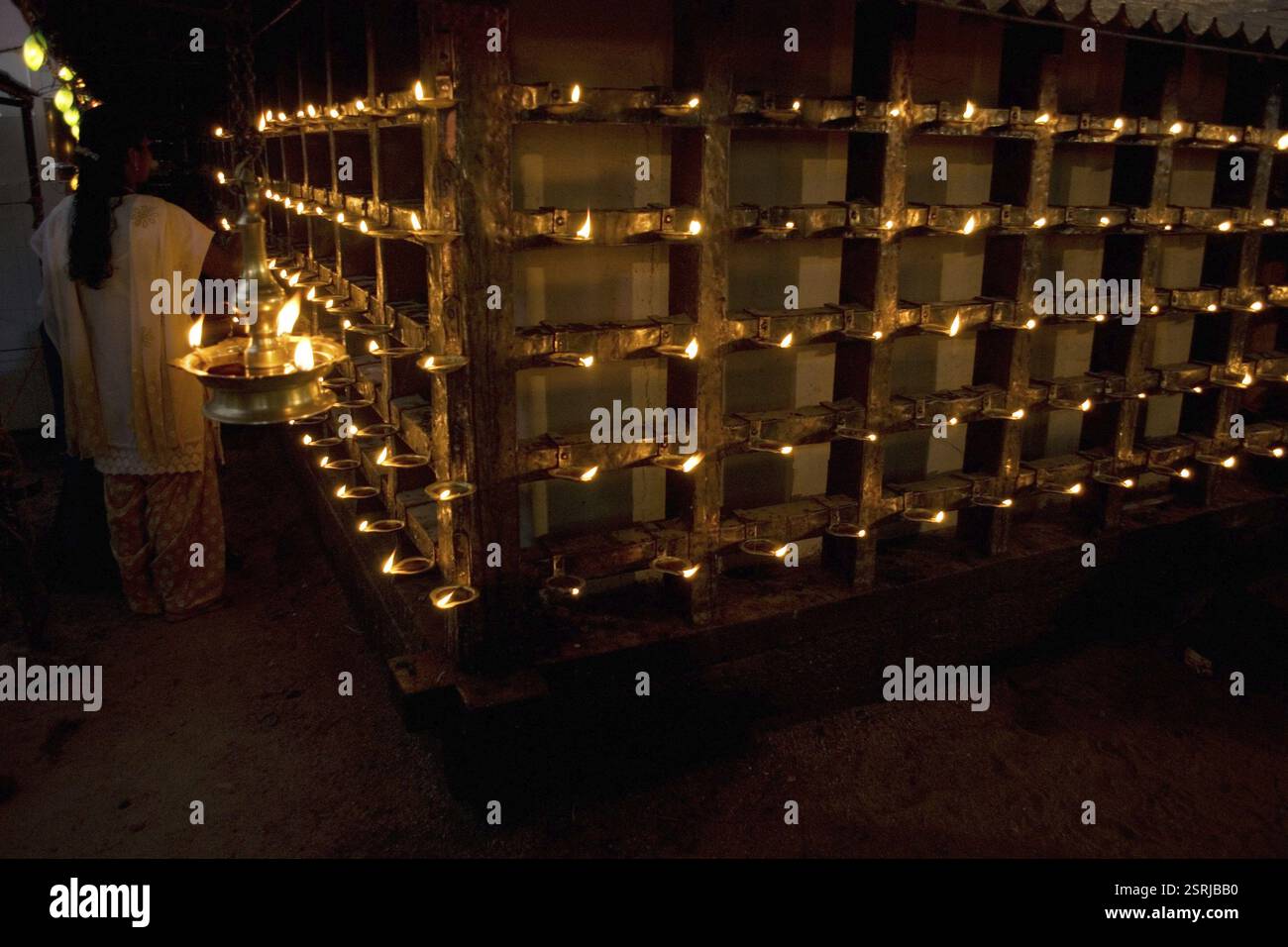 Frau, die Lampe auf Lampenständer im sri kanteshwar Tempel in Trivandrum, Kerala, Indien, Asien anzündet Stockfoto