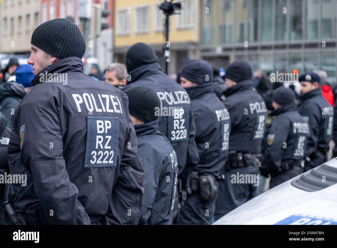 München, Deutschland. Februar 2025. Polizisten bilden eine Kette entlang der Seidlstraße, um zwei Gruppen voneinander zu trennen. Eine spontane Zusammenkunft mit einer menschlichen Kette fand rund um die Gedenkstätte für die Opfer des Angriffs statt, die andere daran hinderte, mehr Blumen zu legen. Dies führte zu Konflikten mit AfD-Anhängern. Die Polizei war mit zahlreichen Polizisten vor Ort. Quelle: Pia Bayer/dpa/Alamy Live News Stockfoto