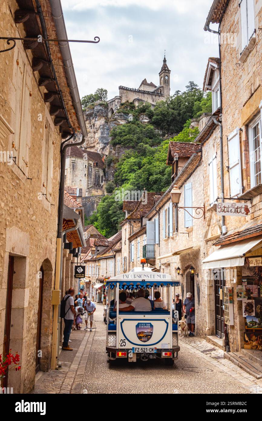 Rocamadour, Frankreich - 18. Juni 2024: Vertikale Fotografie von der Hauptstraße mit einem kleinen touristischen Zug am Fuße des Dorfes Rocamadour, a f Stockfoto