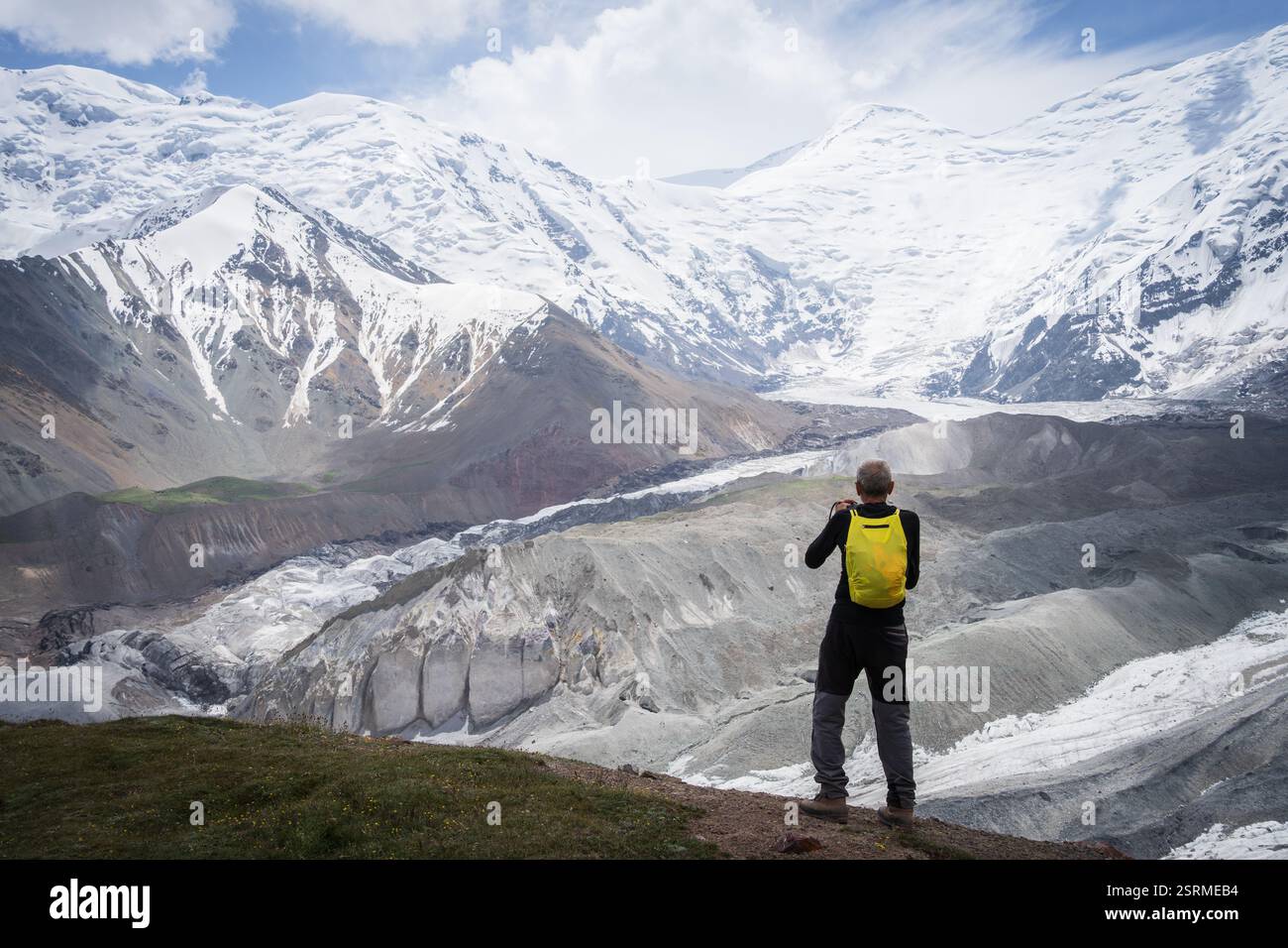 Älterer Mann genießt Aussicht auf schneebedeckte Gipfel und Gletscher vor ihm, Pamir Berge, Kirgisistan Stockfoto