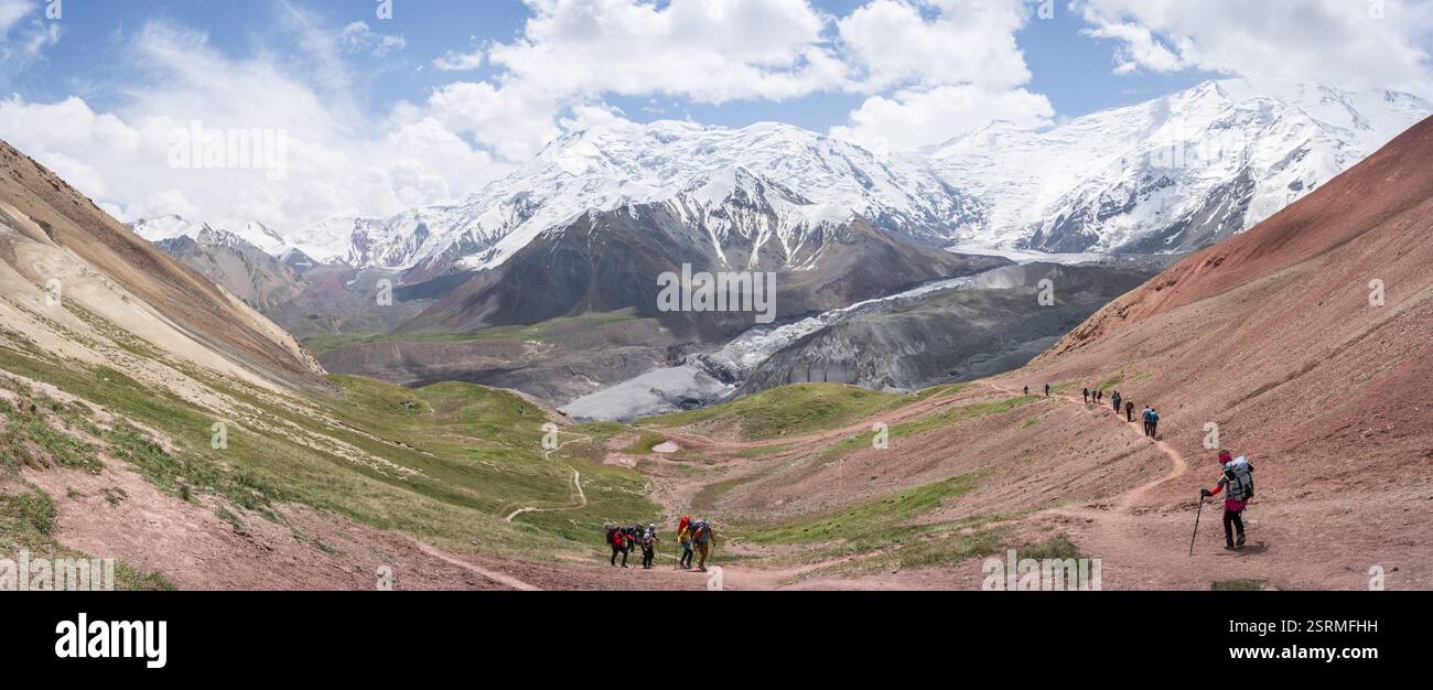 Panoramablick auf die alpine Landschaft mit Gletschern und verschneiten Bergen mit Wandertouristen, Pamir Stockfoto
