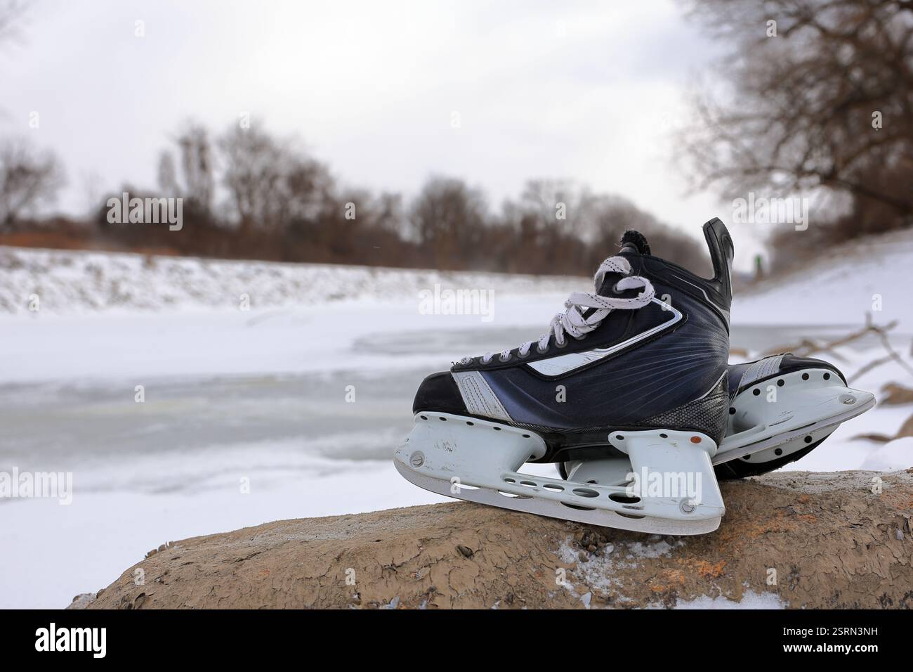 Eishockeyskates bereit für Outdoor-Teichhockey, mit Eis und Schnee im Hintergrund. Stockfoto