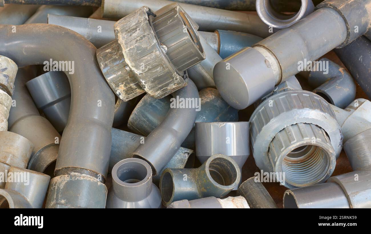 Stapel gebrauchter, entsorgter pvc-Rohre und -Fittings im Vollrahmen, Winkelkupplungen und Rohrabschnitte, Industrie- oder Baustoffrecycling und Abfall Stockfoto