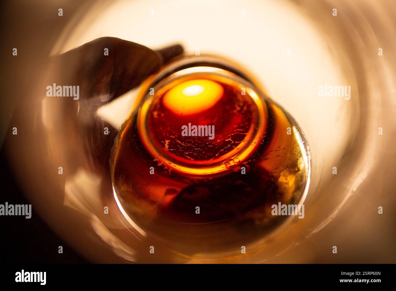 Der Boden eines goldenen Glases Ale scheint in Richtung Kameraobjektiv geneigt zu sein. Stockfoto