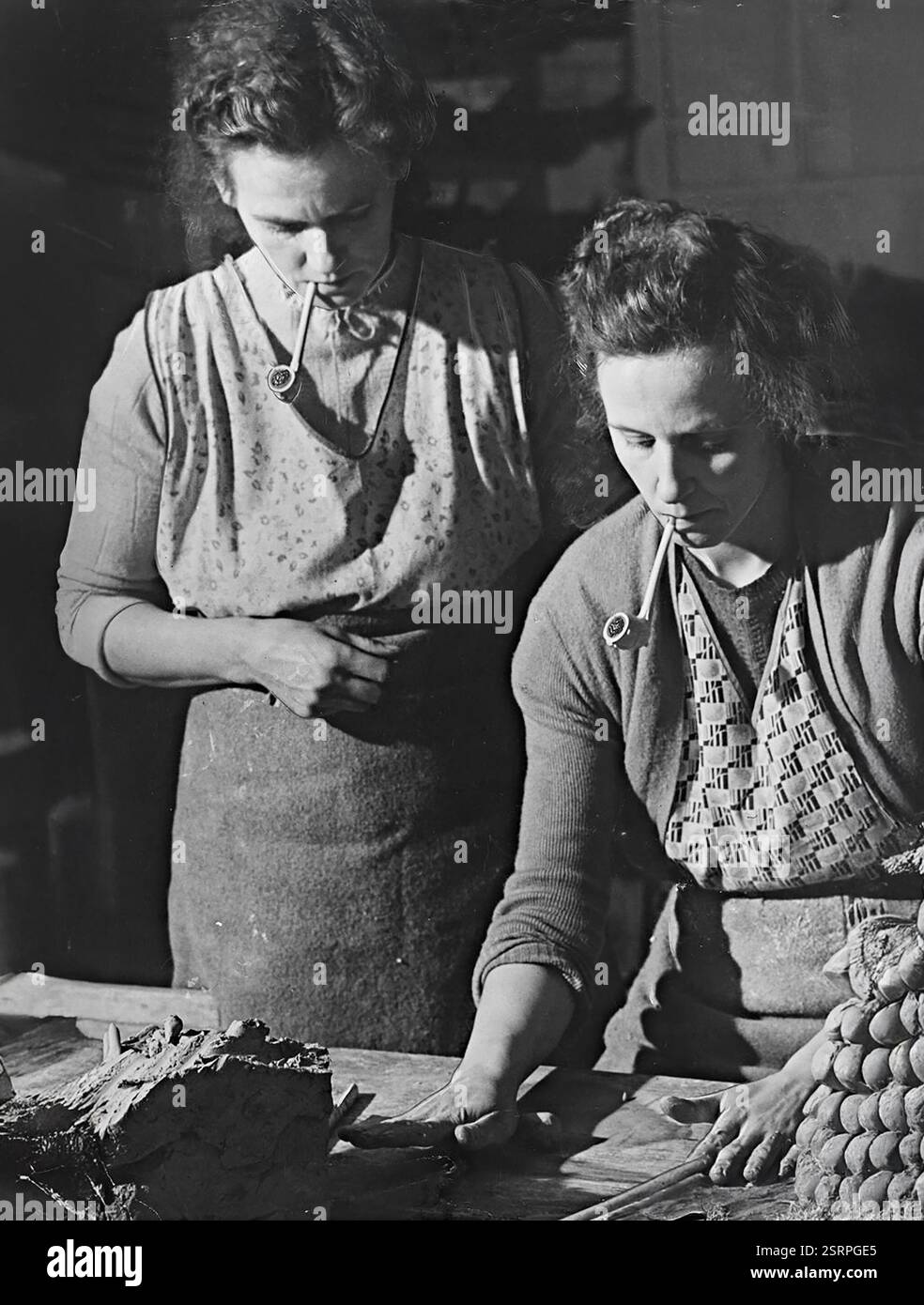 Pfeifenrauchende Frauen, die Tonpfeifen in Broseley in Shropshire herstellen, am 25. Februar 1953 Stockfoto