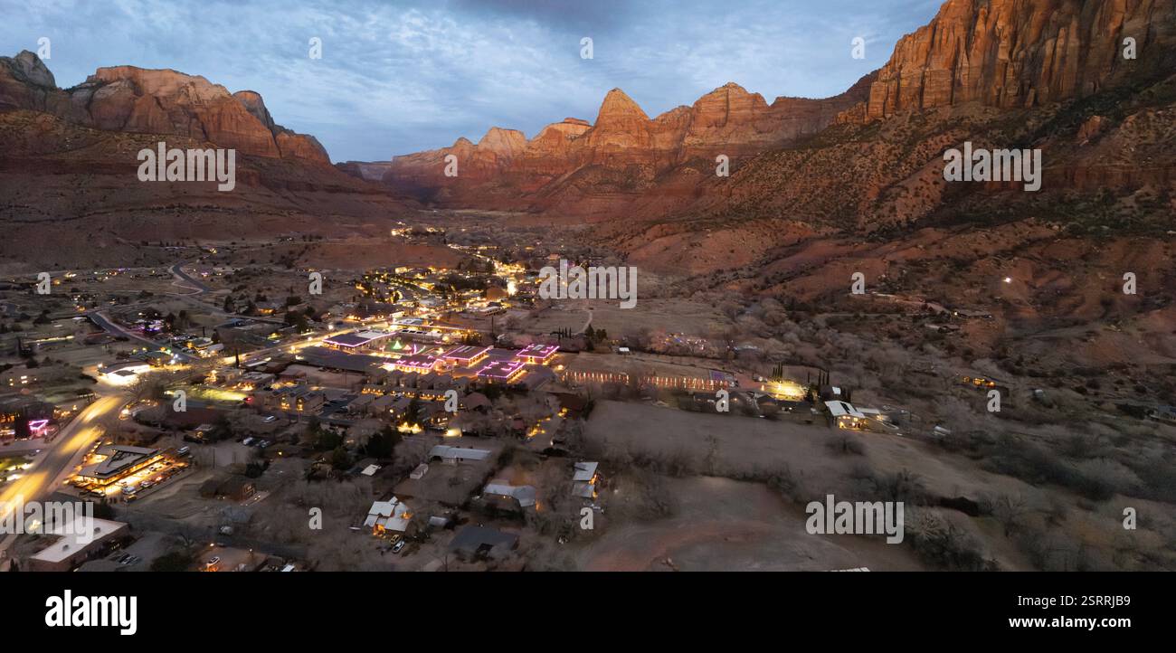 Springdale, Utah, in der Abenddämmerung aus der Vogelperspektive. Die Stadt liegt eingebettet in das Tal des Zion-Nationalparks, beleuchtet von Lichtern. Stockfoto