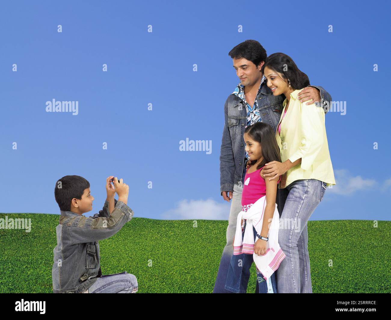 Sohn, klicken auf Foto der Eltern und ihrer Schwester in der Kamera steht auf dem grünen Rasen Stockfoto
