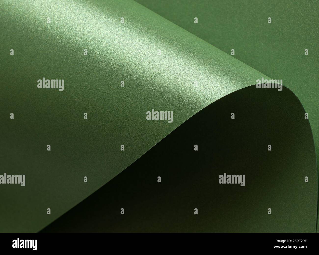 Smaragdgrüner Papierhintergrund mit glänzender, satinierter Textur und schimmernden, welligen Kanten. Tiefe Wald- und Salbeitöne schaffen ein elegantes, luxuriöses und so Stockfoto