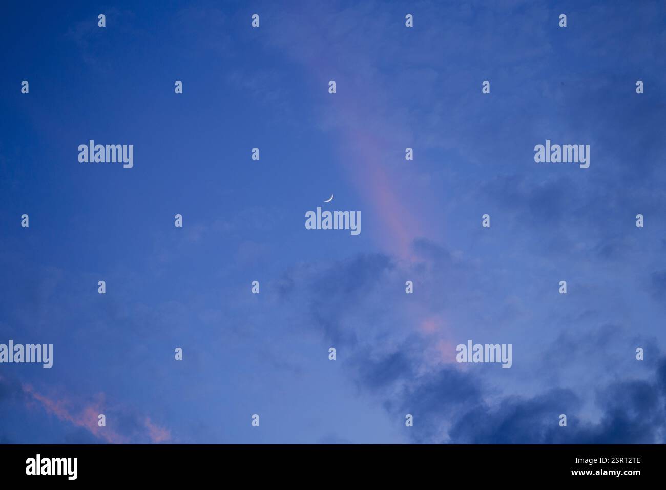 Wachsen des Halbmondes im Hintergrund des blauen und rosa Nachmittagshimmels Stockfoto