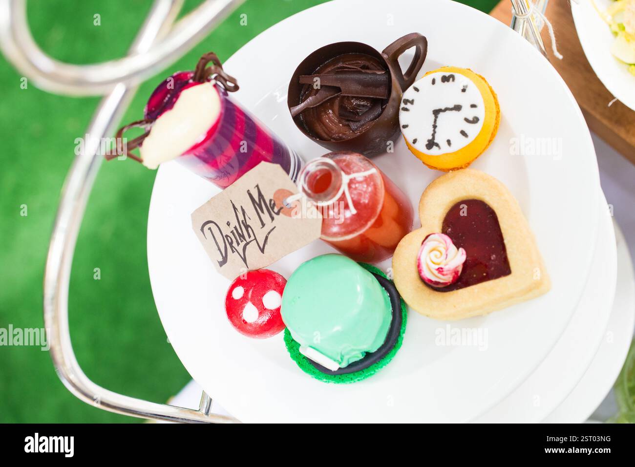 Alice im Wunderland-Thema High Tea. "Trink mich"-Tag, Cupcakes und Kekse auf einem Stufenständer. Stockfoto