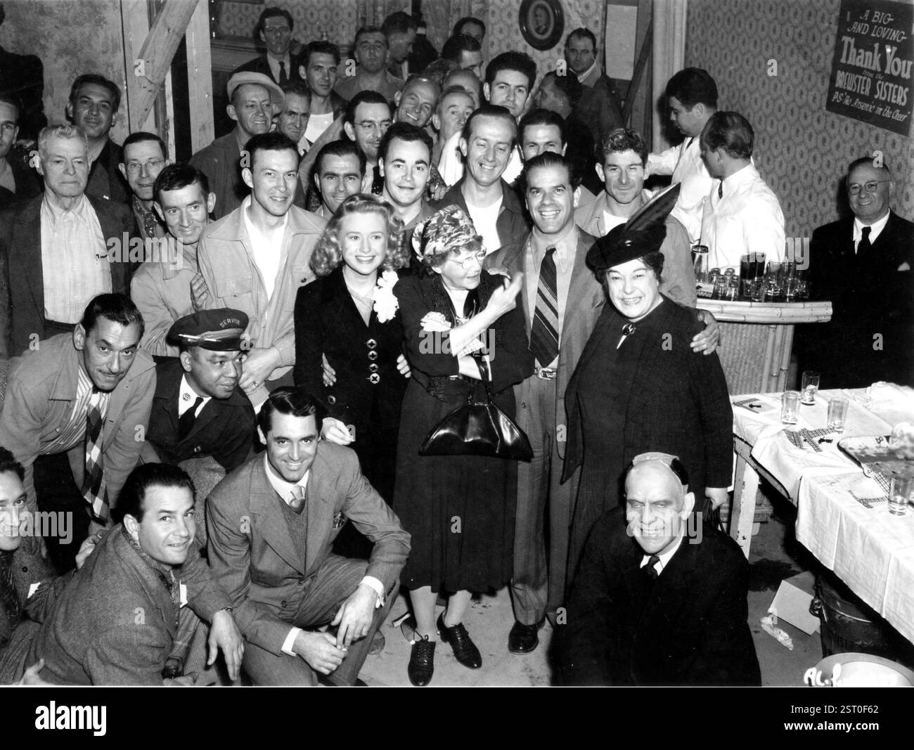 ARSEN UND ALTE SPITZE [US 1944] Cast and Crew Party, CARY GRANT [kniend im Vordergrund], PRISCILLA LANE [hinter Grant in schwarzem Kleid stehend], Regisseur FRANK CAPRA [rechts von der Mitte mit gestreifter Krawatte], JOSEPHINE HUTCHISON [gefiederter Hut], RAYMOND MASSEY [vorne, unten rechts] Datum: 1944 Stockfoto