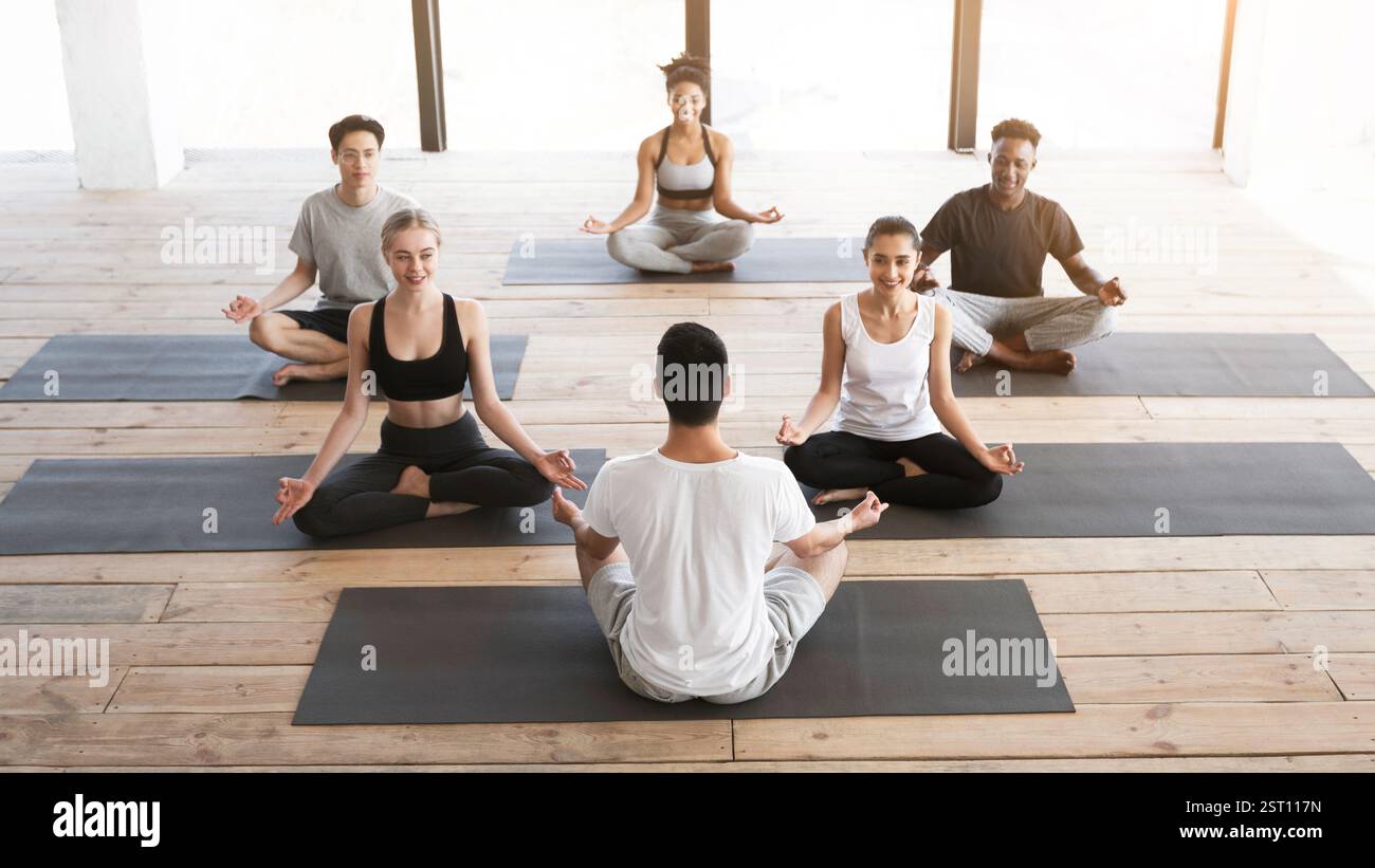 Gruppe junger Leute, die Yoga-Kurs mit Trainer im Studio Stockfoto