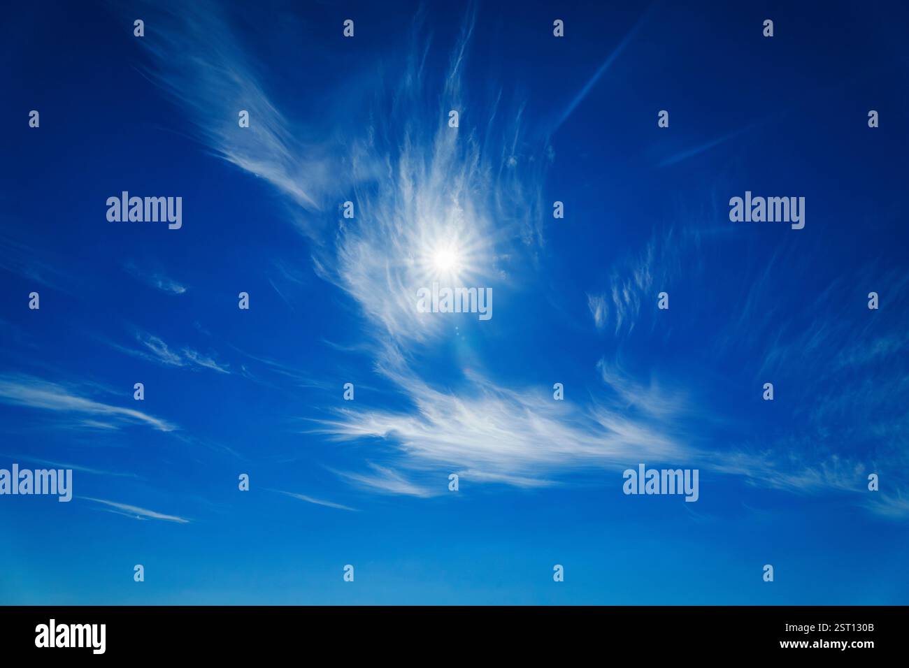 Helle Sonne, die durch wackelige Wolken im blauen Himmel scheint Stockfoto