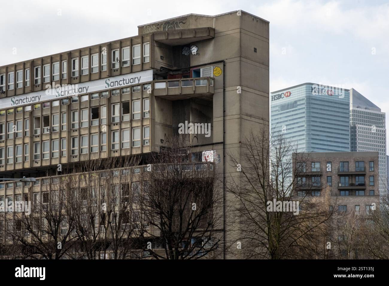 Robin Hood Gardens, brutalistischer Turmblock mit Canary Wharf und HSBC Tower im Hintergrund. Stockfoto