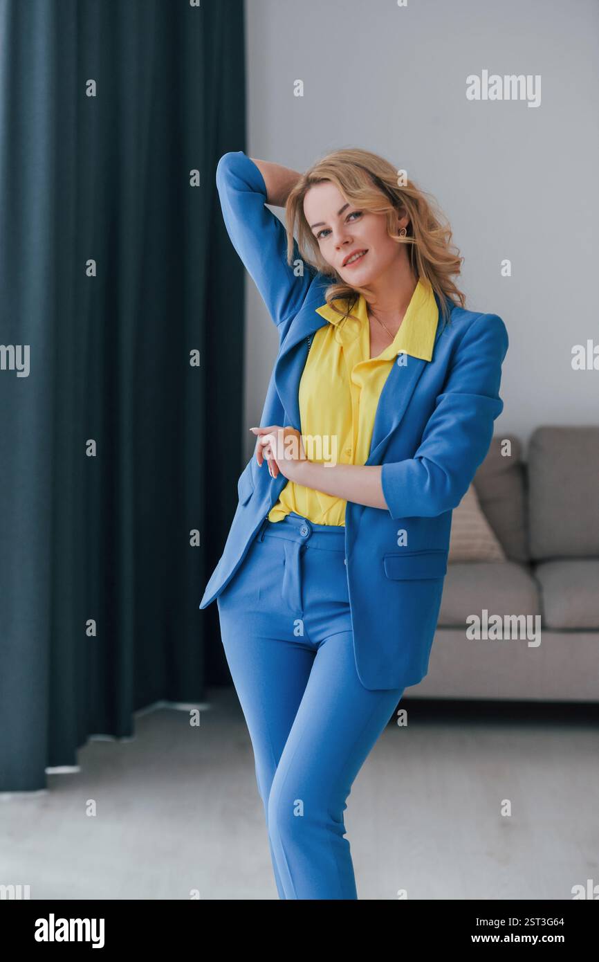 Frau in formellem blau-gelben Hosenanzug ist drinnen. Stockfoto