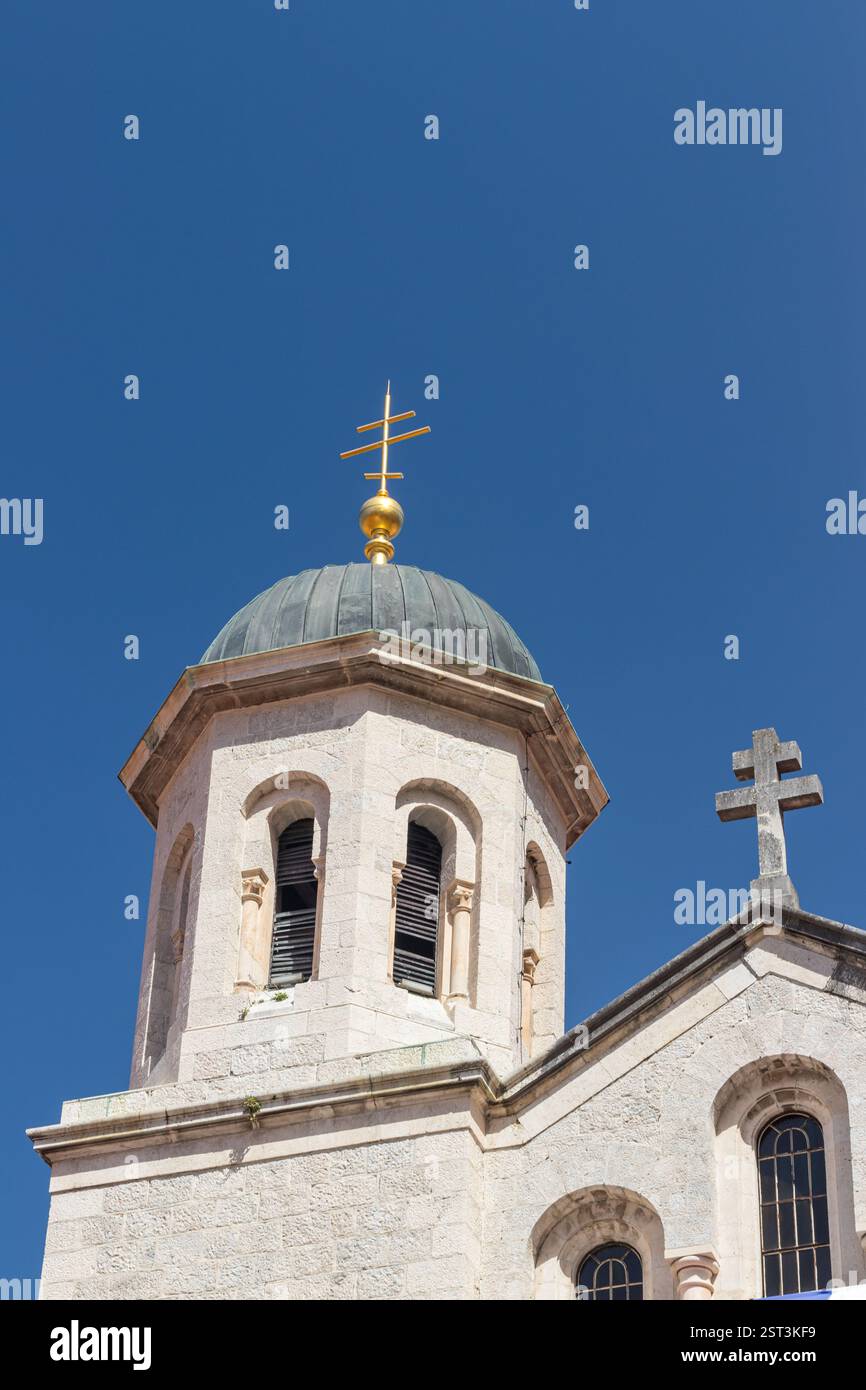 Eine traditionelle Kirche mit Mauerwerk und Glockentürmen vor einem leuchtend klaren blauen Himmel. Die architektonischen Details und das harmonische Design spiegeln seine wider Stockfoto