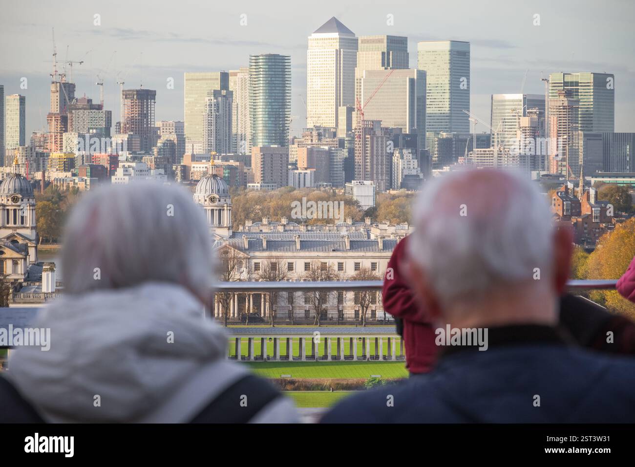 Zwei ältere Menschen überblicken die historischen Gebäude von Greenwich mit den modernen Wolkenkratzern der Canary Wharf im Hintergrund Stockfoto