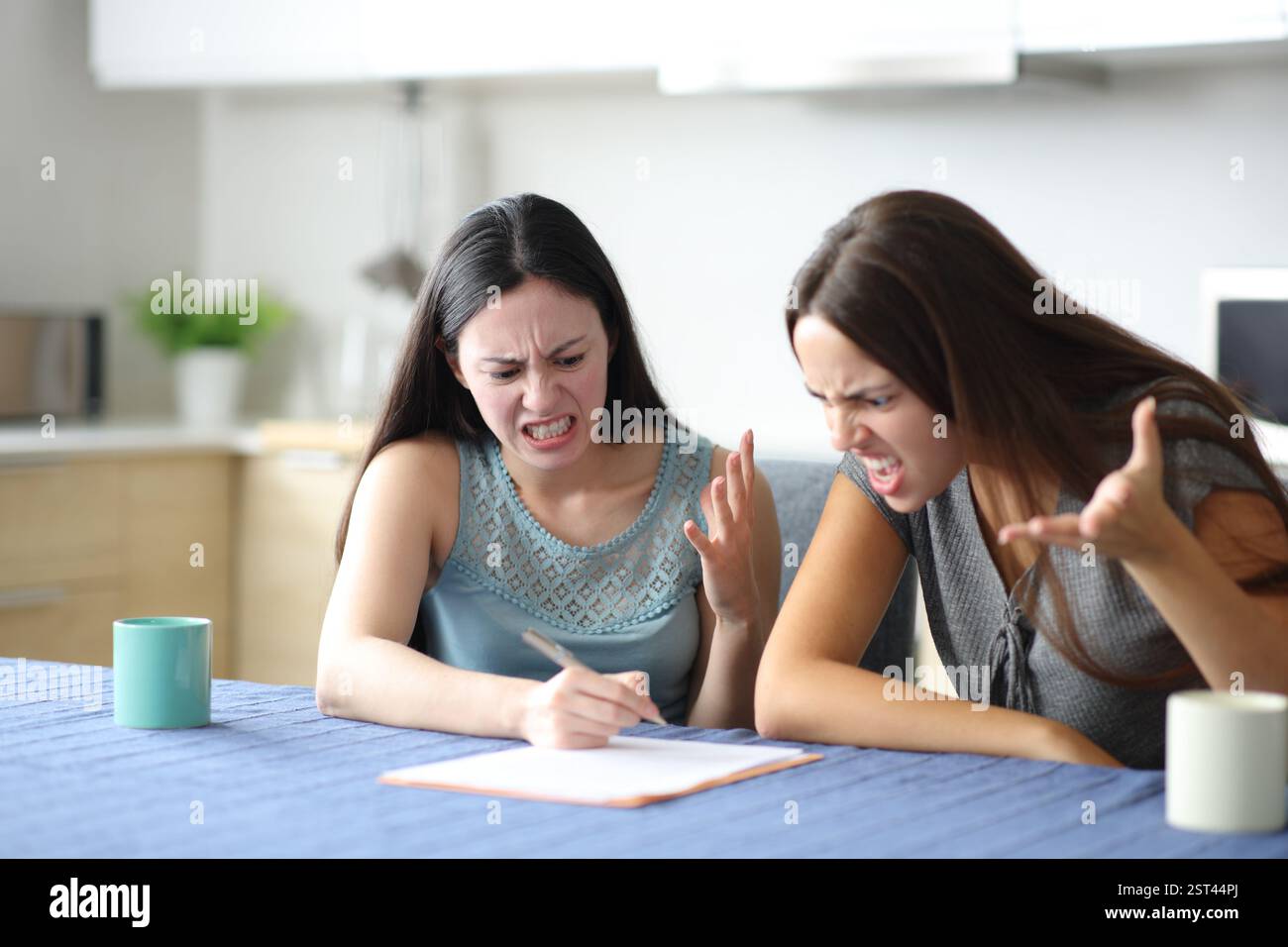 Wütende Mitbewohner, die in der Küche zu Hause einen Papiervertrag lesen Stockfoto