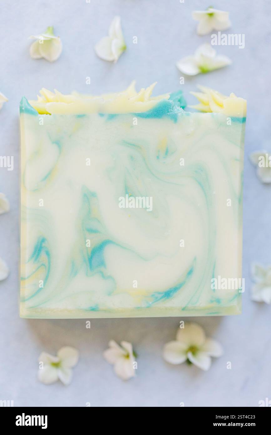Handgefertigte Seife mit blauen und gelben Wirbeln und zarten Blumendetails Stockfoto
