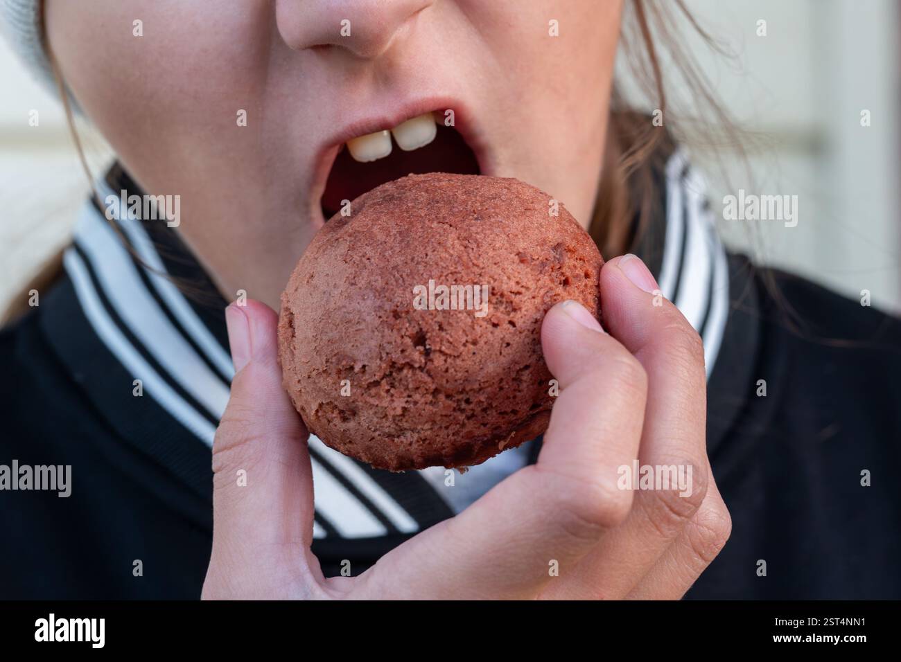 Mädchen Isst Zuckerhaltigen Donut. Mädchen isst Kuchen im Winter, Porträt eines schönen Mädchens mit Schokoladendonut. Stockfoto