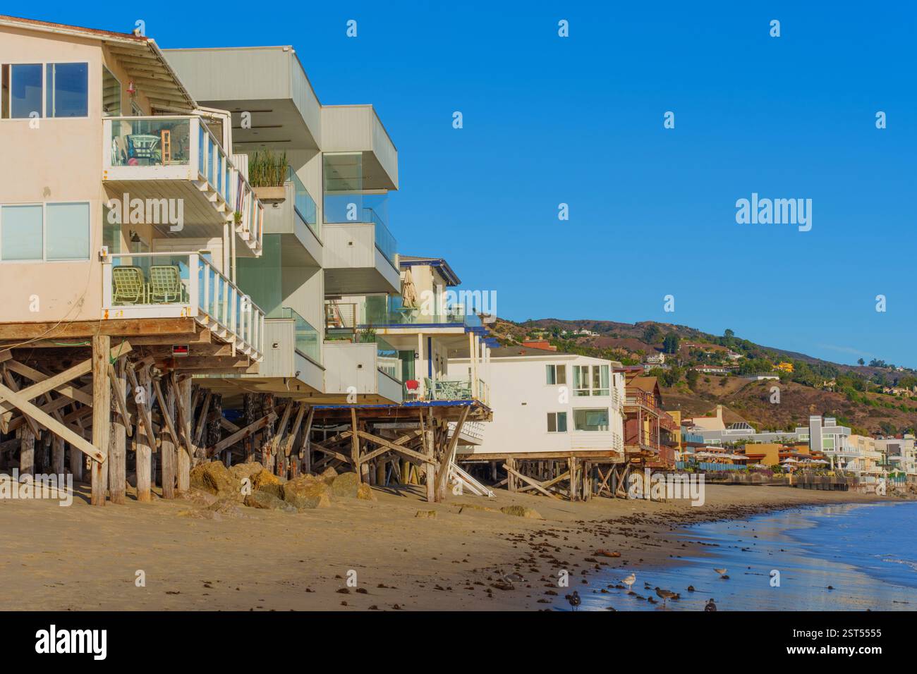 Malibu, Kalifornien - 29. November 2024: Stelzenhäuser am Strand in Malibu mit moderner Architektur, eingerahmt von Sandstrand und klarem blauem Himmel Stockfoto