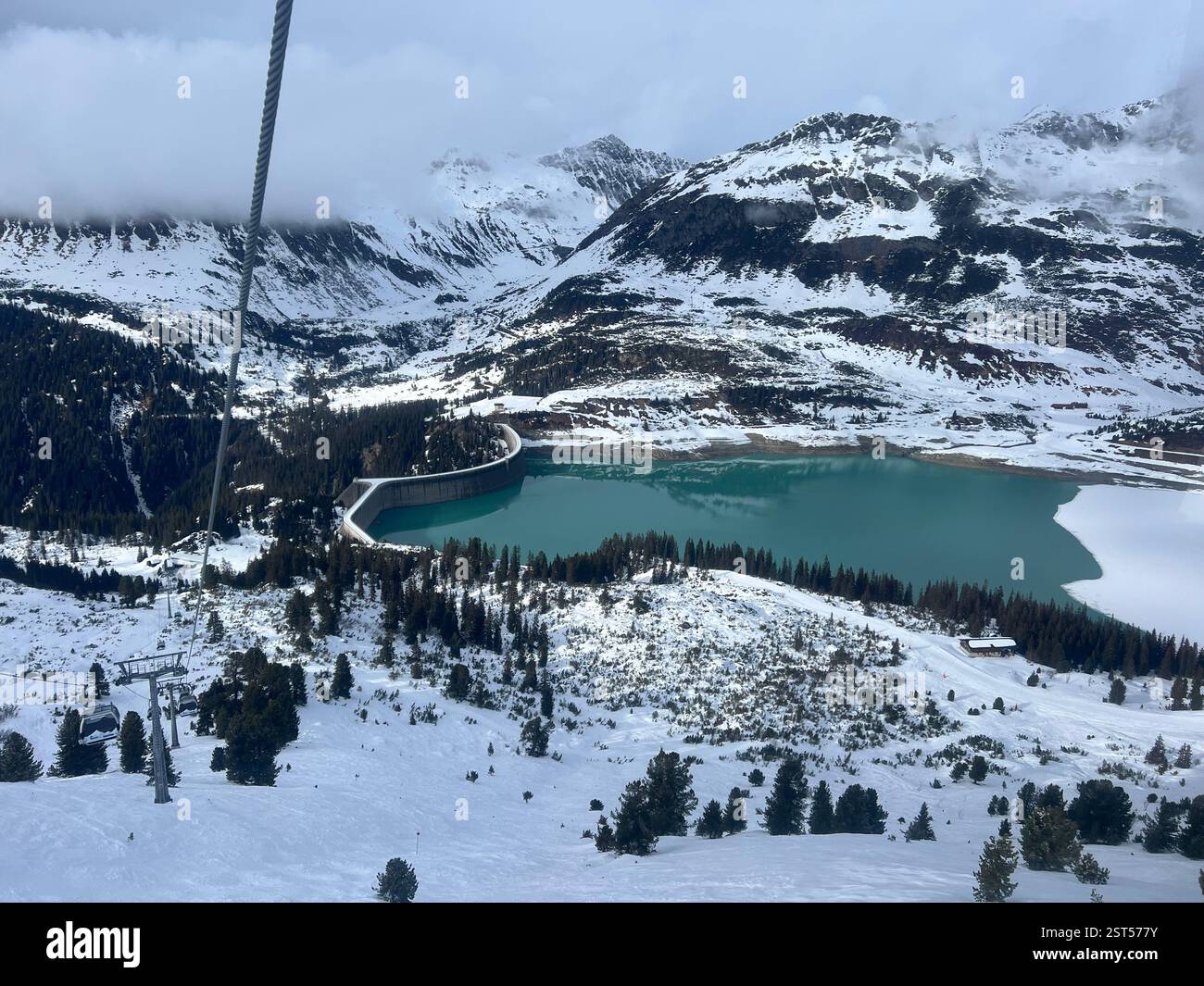 Blick über den Kopssee bei Galtür und die Skigebiete Ischgl in Tirol im Winter vom Skilift aus. Das Wasser ist von der rechten Seite gefroren. - Smartphone-aufgenommenes Stockfoto