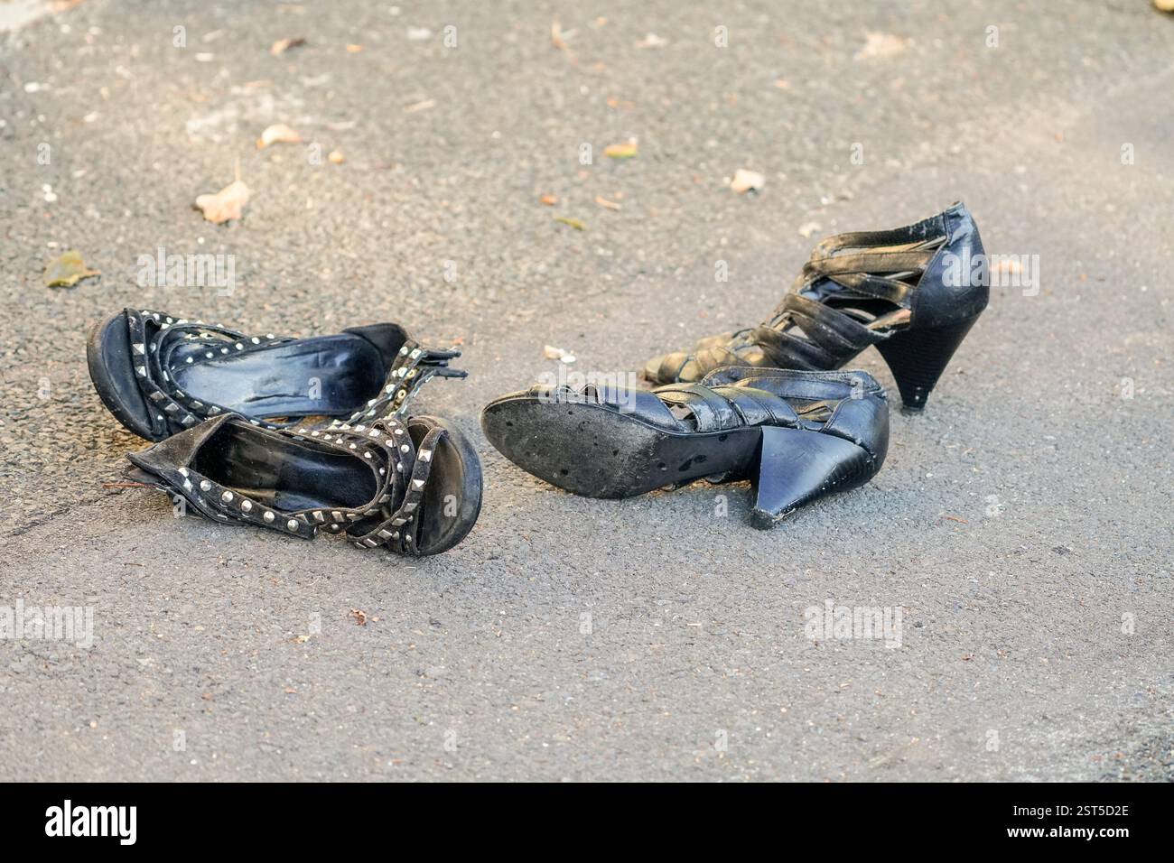 Zwei Paar alte schwarze Damenschuhe liegen verlassenen oder vergessenen auf einer Straße oder einem Bürgersteig Stockfoto