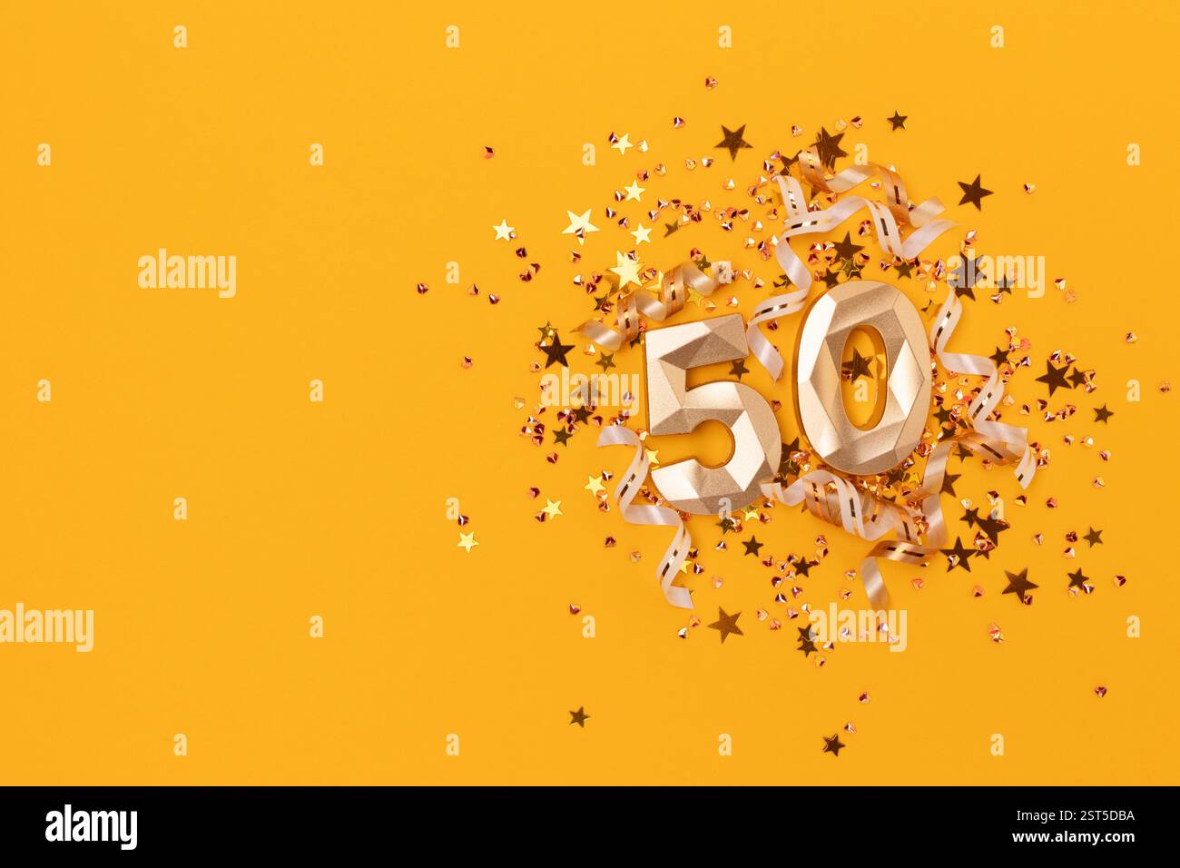 Goldene Zahl fünfzig, Bänder und Sternenkonfetti auf gelbem Hintergrund. Glühende Zusammenstellung mit Platz für Text. Stockfoto