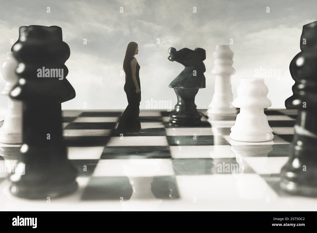 Schwarz gekleidete Frau, die Schach spielt, als Schachfigur oder Königin; abstraktes Konzept Stockfoto