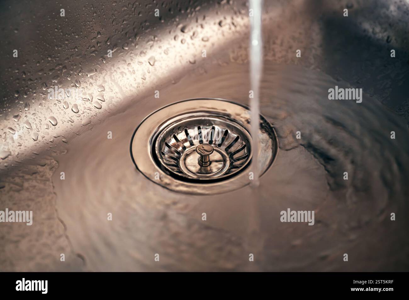 Wasser im neuen Abfluss aus metallischem Spülbecken, selektiver Fokus Stockfoto