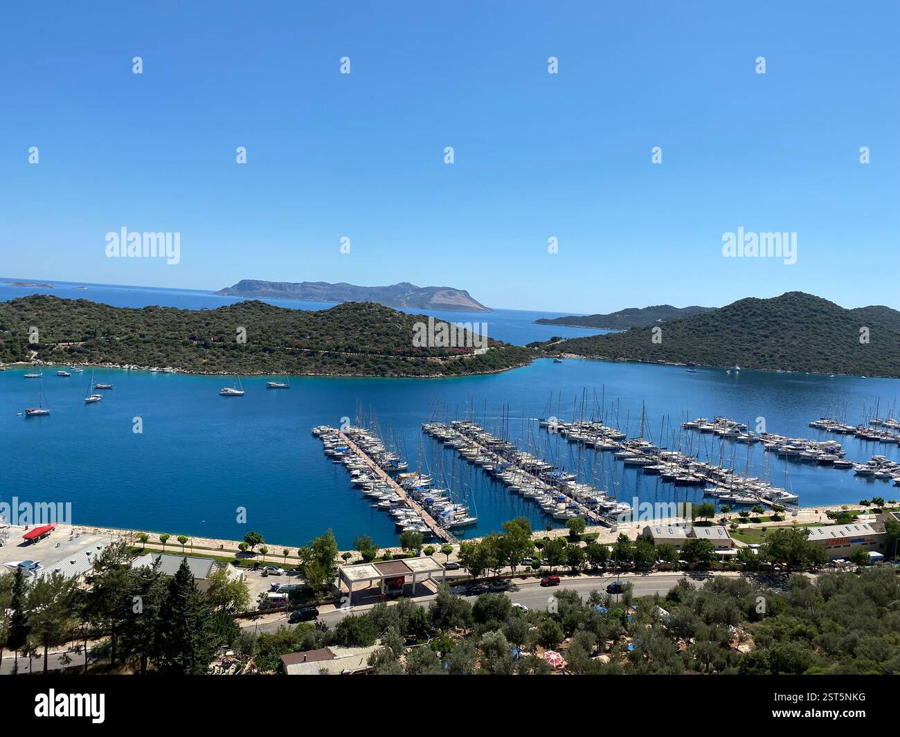 Blick auf einen Hafen, Boote und baumbedeckte Berge - Smartphone-aufgenommenes Stockfoto