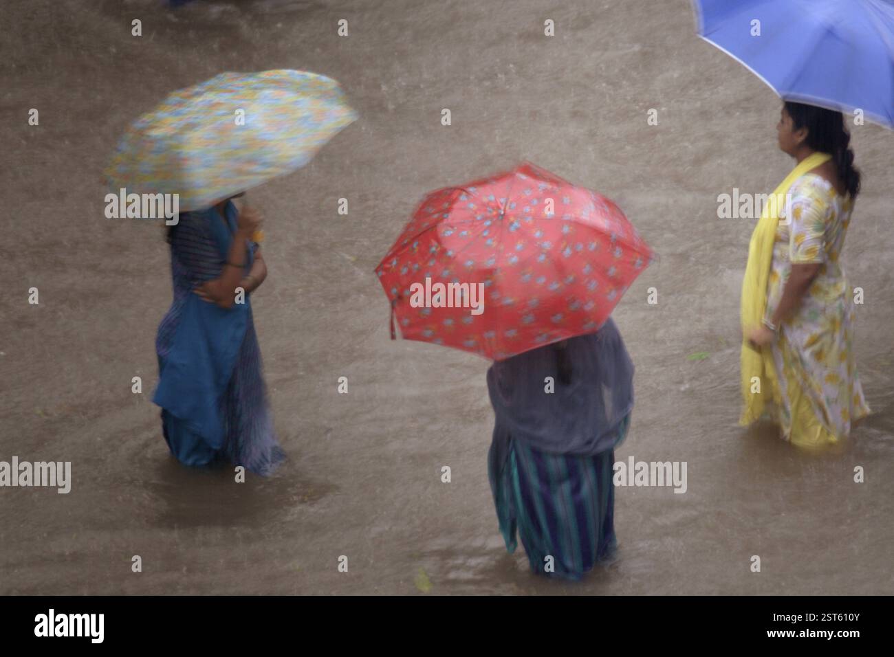 Drei Frauen gehen mit einem farbigen Regenschirm in überflutetem Wasser, Monsun, Weltrekordregen in Kalyan, Bombay, jetzt Mumbai, Maharashtra, Indien, ASI Stockfoto