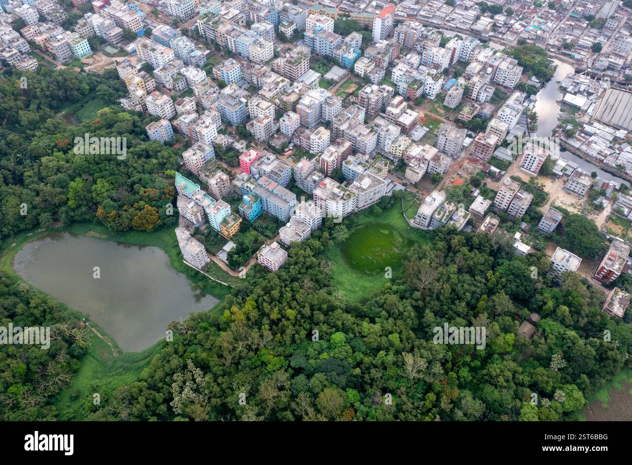 Ein Blick aus der Vogelperspektive auf den National Botanical Garden von Dhaka, der üppiges Grün neben der urbanen Landschaft bietet, mit einem Blick auf das Wohngebiet Stockfoto