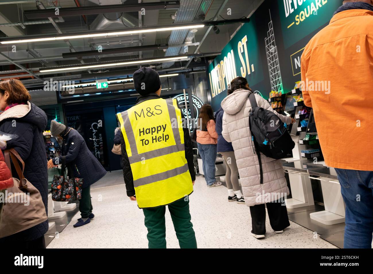 M&S Marks and Spencer Worker helfen gerne beim Anmelden der Uniform und helfen Kunden beim Self-Service-Check-out im Laden London England UK KATHY DEWITT Stockfoto