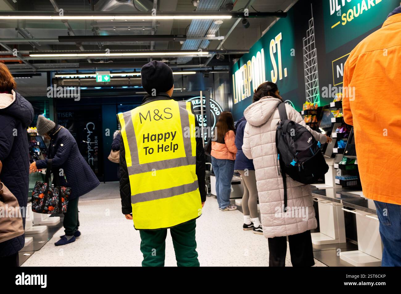 M&S Marks and Spencer Worker helfen gerne beim Anmelden der Uniform und helfen Kunden beim Self-Service-Check-out im Laden London England UK KATHY DEWITT Stockfoto