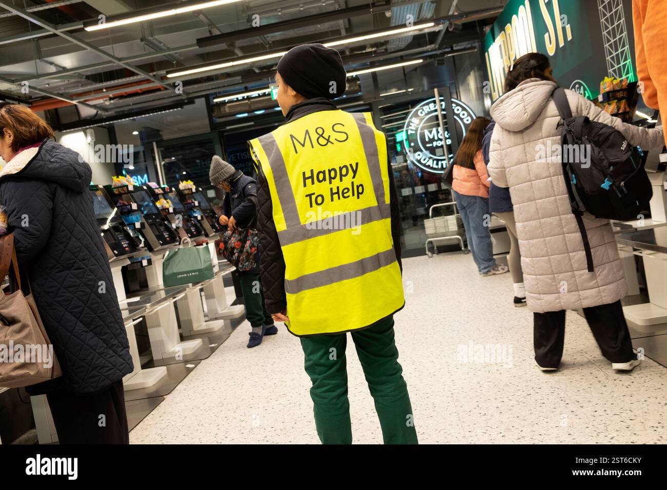 M&S Marks and Spencer Worker helfen gerne beim Anmelden der Uniform und helfen Kunden beim Self-Service-Check-out im Laden London England UK KATHY DEWITT Stockfoto