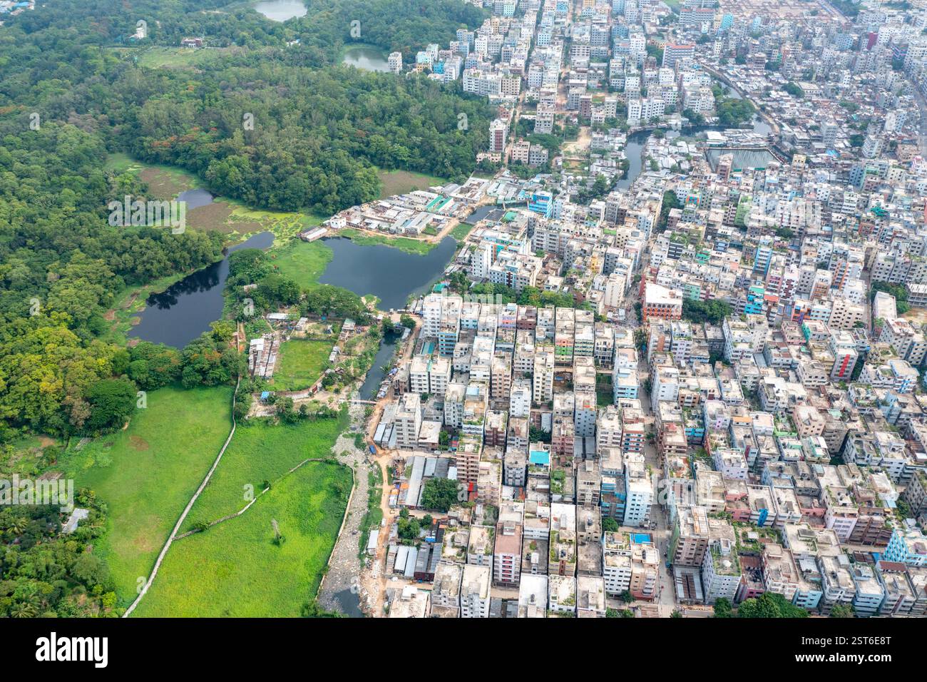 Ein Blick aus der Vogelperspektive auf den National Botanical Garden von Dhaka, der üppiges Grün neben der urbanen Landschaft bietet, mit einem Blick auf das Wohngebiet Stockfoto