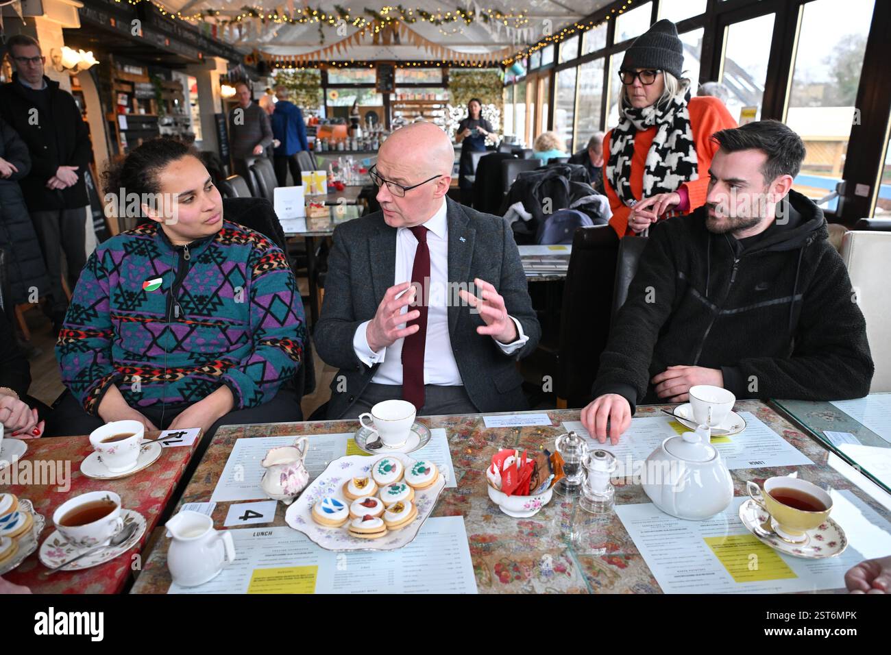 Der erste schottische Minister John Swinney (Mitte) spricht mit der Praktikantin Iona Foulis während eines Besuchs der neuen schottischen Fernsehsendung Summerwater, die auf der North Ballochruin Farm in Glasgow gedreht wird. Summerwater, basierend auf dem Roman von Sarah Moss, erhielt 700.000 £ über den Broadcast Content Fund von Screen Scotland, der von der schottischen Regierung unterstützt wird. Bilddatum: Montag, 17. Februar 2025. Stockfoto