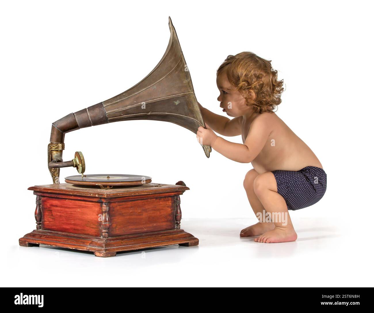 Baby wird neugierig durch ein altes Gramophon Stockfoto