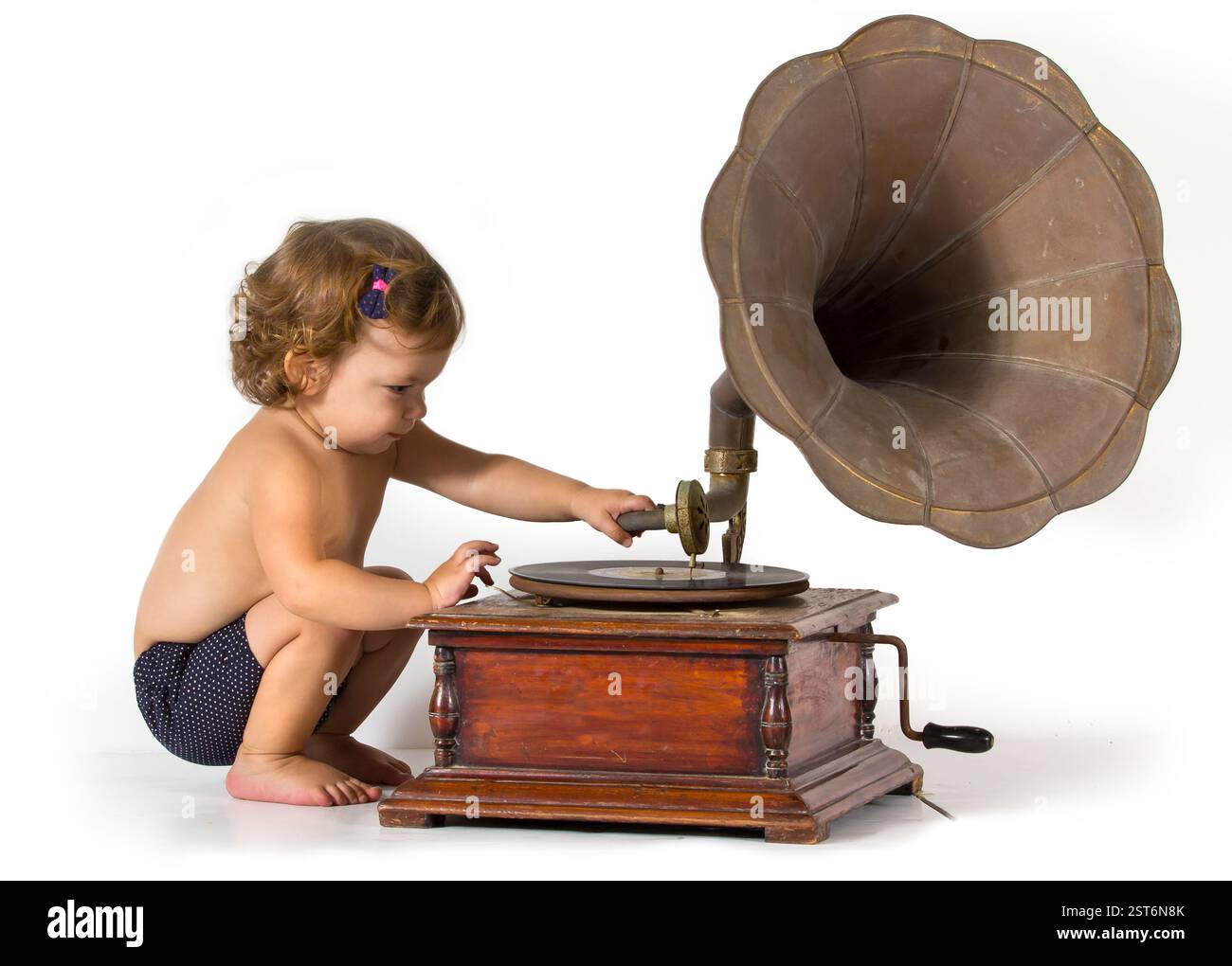 Baby wird neugierig durch ein altes Gramophon Stockfoto