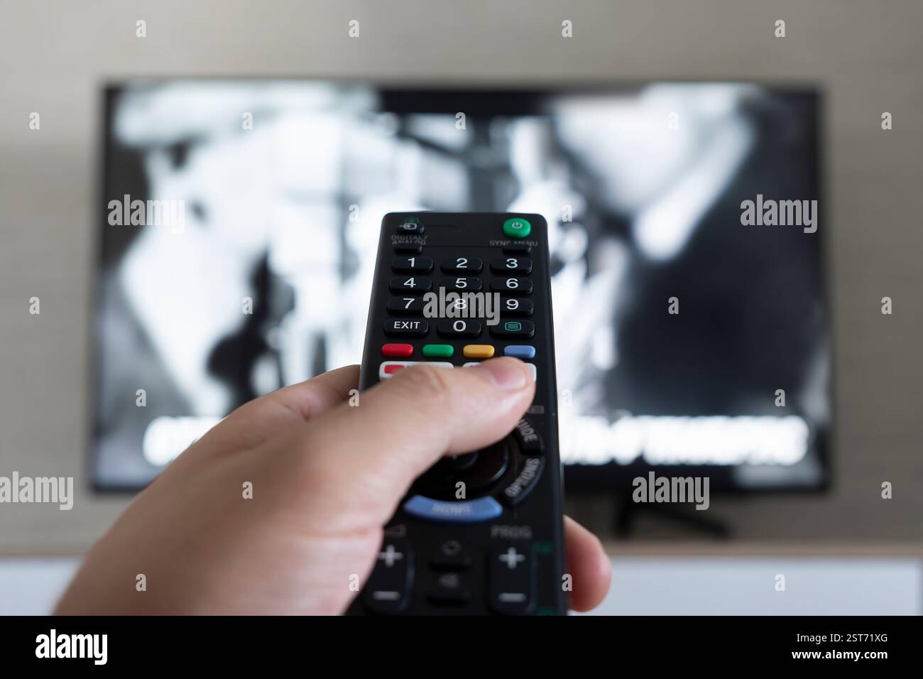 Männer mit der Fernbedienung des Fernsehers. Hand mit Fernbedienung auf den Fernseher gerichtet. Ein Mann ist Entspannung und Sport im Fernsehen ansehen. Stockfoto