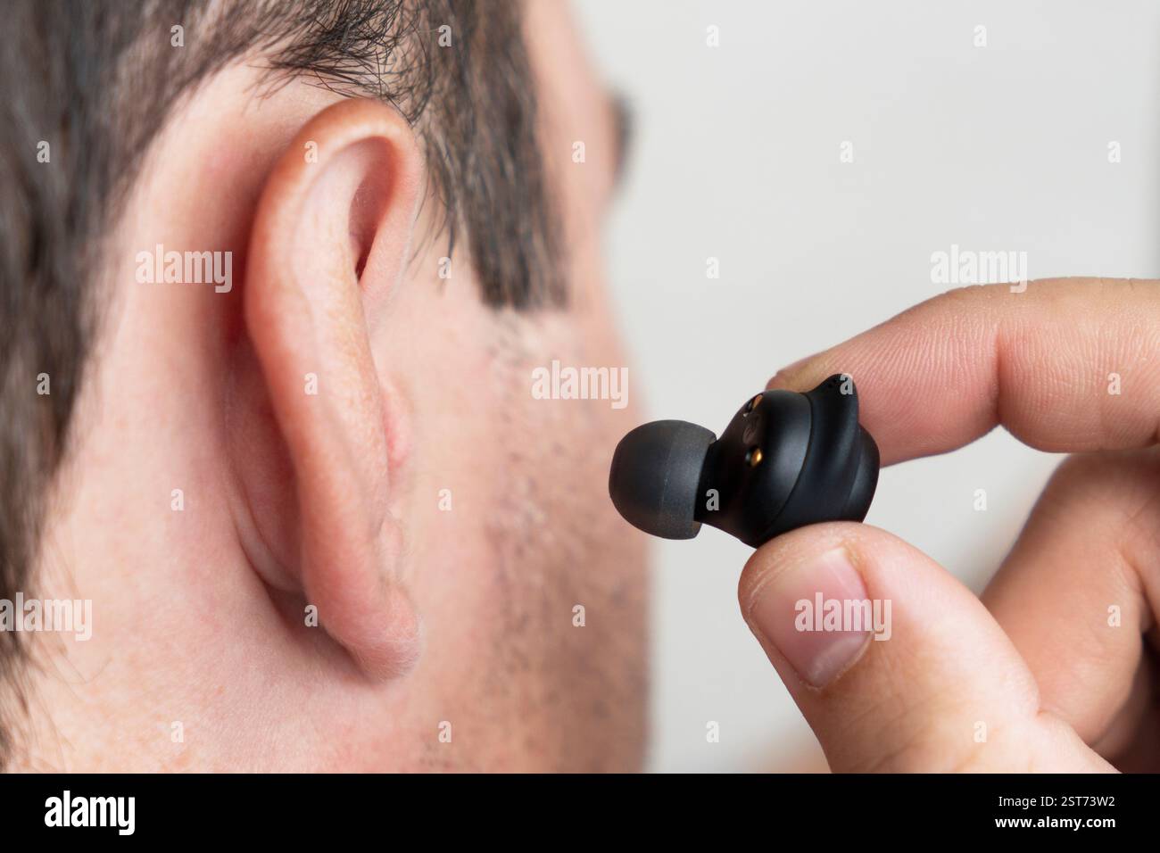 Nahaufnahme eines schnurlosen Ohrhörers im menschlichen Ohr auf weißem Hintergrund. Stecken Sie den Kopfhörer in das Ohr Stockfoto