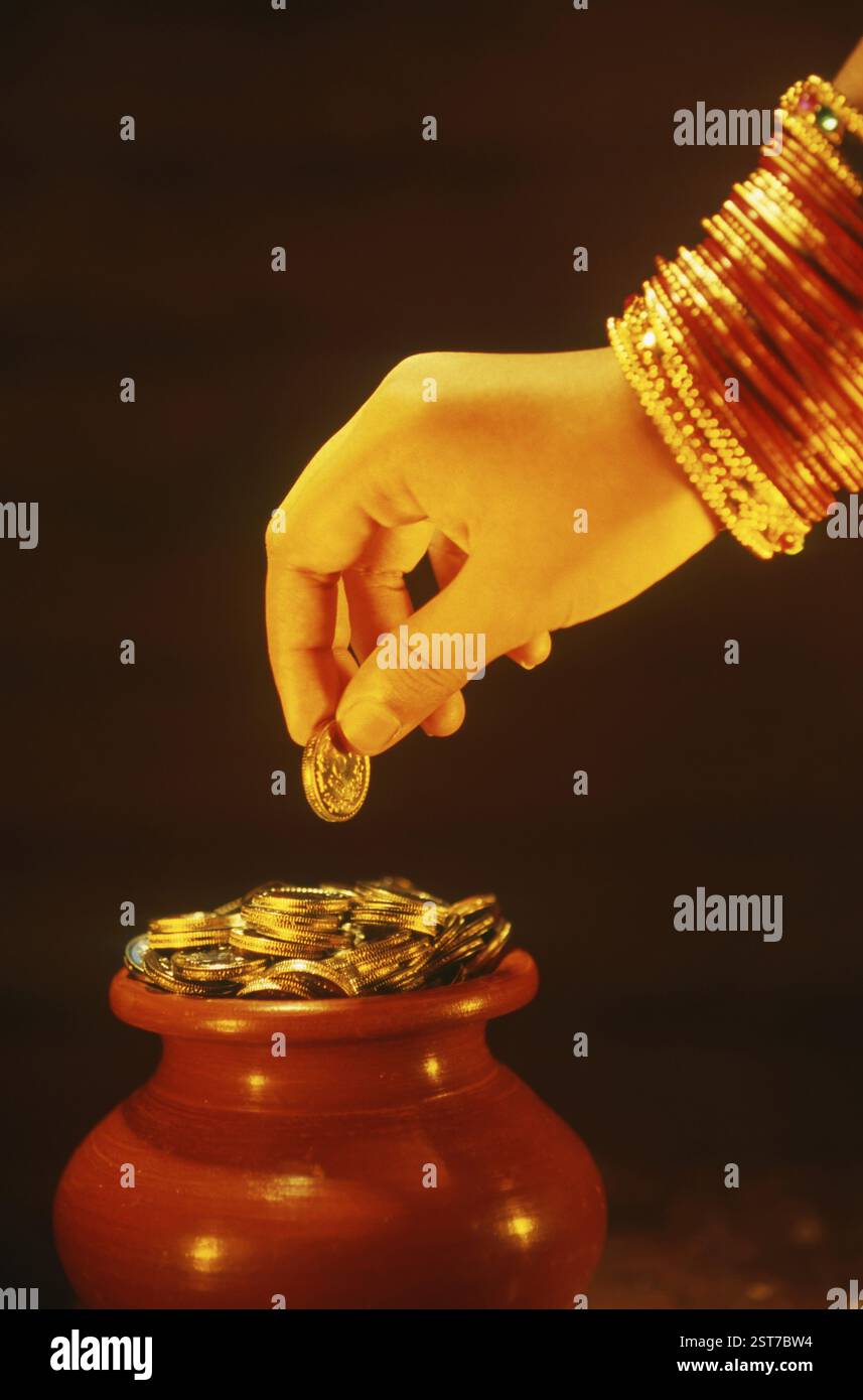Frau, die eine Münze über dem irdenen Münztopf hält MR. 201 Stockfoto