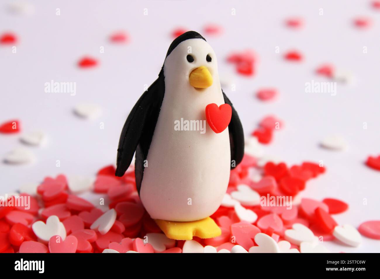 Pinguin mit Herz auf der Brust, umgeben von kleinen Herzen Stockfoto